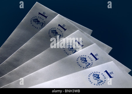 ENVELOPES Pre-paid UK first class envelopes on dark blue background with dappled shafts of sun Stock Photo