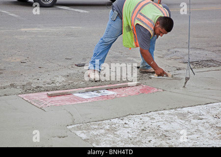Workers install a curb ramp at a street intersection to allow access ...