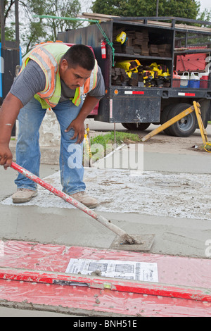 Workers install a curb ramp at a street intersection to allow access ...