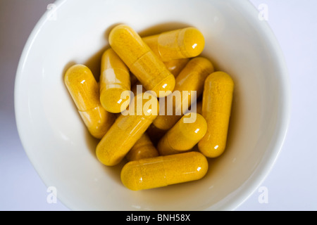 Turmeric capsules in a white dish Stock Photo