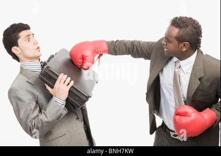 Businessman defending himself from the punch of his colleague Stock Photo