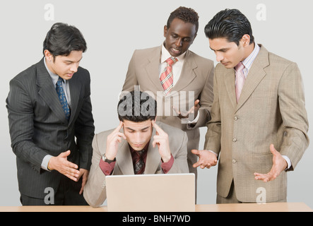 Four businessmen looking stressed in front of a laptop Stock Photo