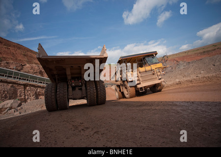 Heavy earth mover mining haul dump trucks in open case mine passing each other on way out and into mining quarry Stock Photo