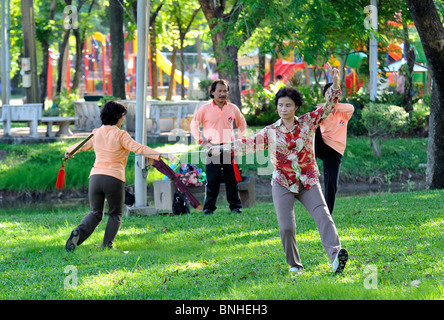 Woman performing Tai Chi exercises with a large sword in Lumpini Park, Bangkok Stock Photo