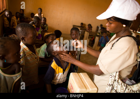 A community health nurse vaccinates children against polio at the Gbulahabila primary school in the village of Gbulahabila Stock Photo