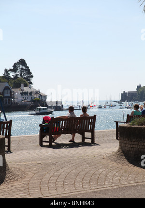 two people sat on bench looking at sailing boats Stock Photo