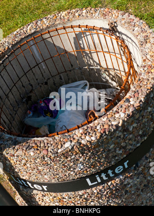 Close up view of concrete litter bin with rubbish placed in the internal wire basket Stock Photo