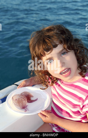 Girl with two jellyfish in white dish on boat blue mediterranean sea