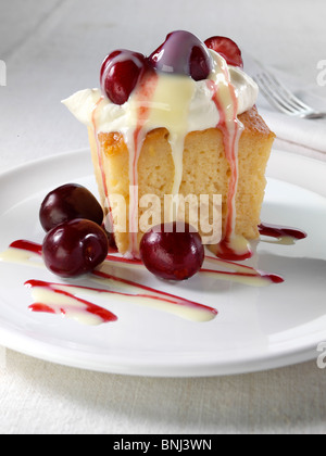 Spanish traditional sponge cake with evaporated and condensed milk topped with whipped cream and fruit Stock Photo