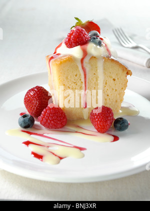 Spanish traditional sponge cake with evaporated and condensed milk topped with whipped cream fruit and coulis Stock Photo