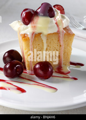 Spanish traditional sponge cake with evaporated and condensed milk topped with whipped cream and fruit Stock Photo