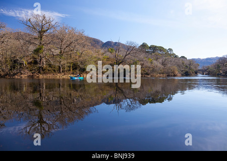 Canoeist paddling canoe past Meeting of Waters Mucross Lake Killarney Ring of Kerry Co. in spring sunshine County Munster Republ Stock Photo