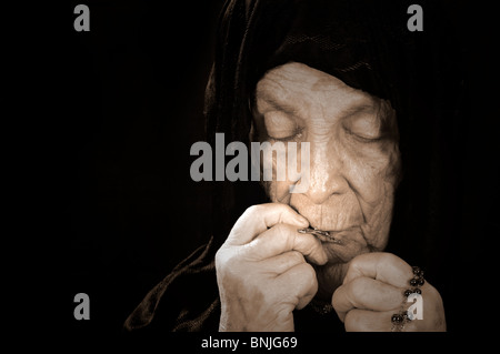 Old Woman Deep in Prayer wearing a black Veil Stock Photo