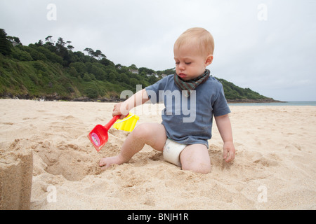 Baby boy 14 months old playing on the beach with a bucket and spade Carbis Bay beach, St Ives, Cornwall, England, United Kingdom. Stock Photo