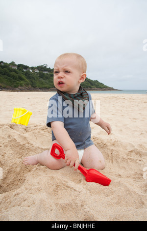 Baby boy 14 months old playing on the beach with a bucket and spade Carbis Bay beach, St Ives, Cornwall, England, United Kingdom. Stock Photo