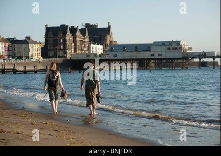 A young couple walking along the beach at Aberystwyth Wales UK on a summer evening Stock Photo