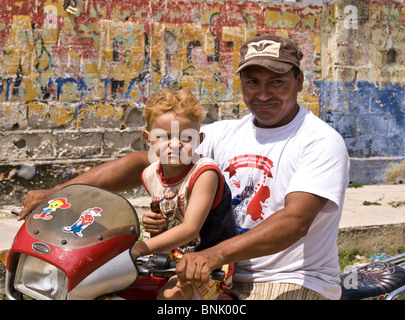 Father and son on their motorbike which, apart from donkeys, is the only mode of transport in the fishing village of Baru. Stock Photo