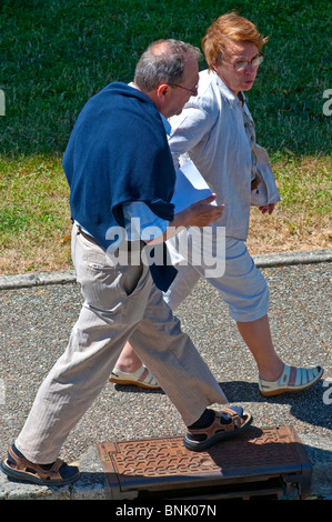 Mature / middle-aged couple walking along pavement - France. Stock Photo