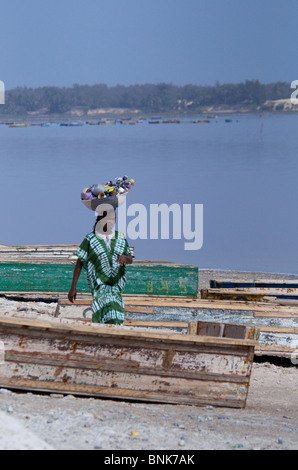 Africa, Senegal, Dakar. The Pink Lake of Retba. Salt gathering boats on Retba lake. Female vendor with basket of souvenir dolls. Stock Photo