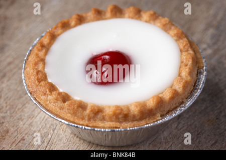 a small cherry bakewell tart cake in mass produced silver foil cup Stock Photo