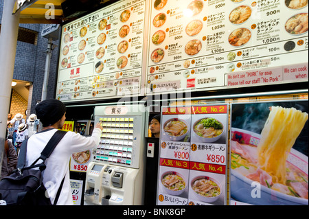 Using ticket dispensing machine to order food at cheap ramen and noodle eatery, Tokyo, Japan Stock Photo