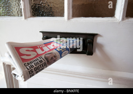A copy of the English newspaper, The Sun, delivered to a house and sticking out of the letterbox Stock Photo