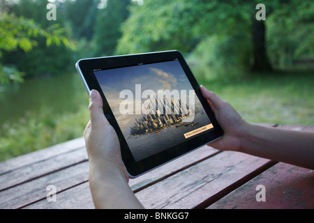 A woman waiting Financial Times iPad applications loading on her iPad on outdoor setting Stock Photo