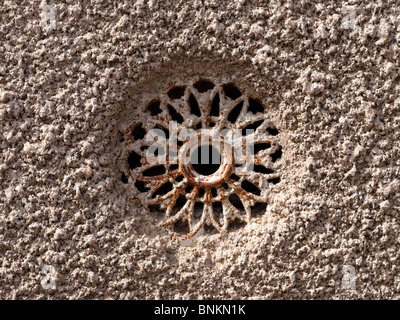 Old patterned metal air vent in pebbledash wall - France. Stock Photo