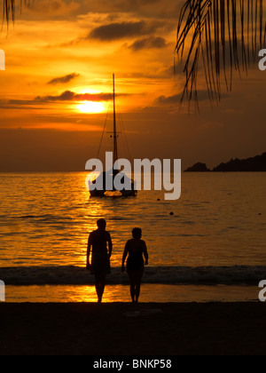 Sunset with sailboat and couple silhouetted in Zihuatanejo, Mexico Stock Photo