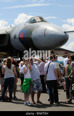 Visitors to the Farnborough Air Show standing below a historic Vulcan bomber aircraft to watch the flying display Stock Photo