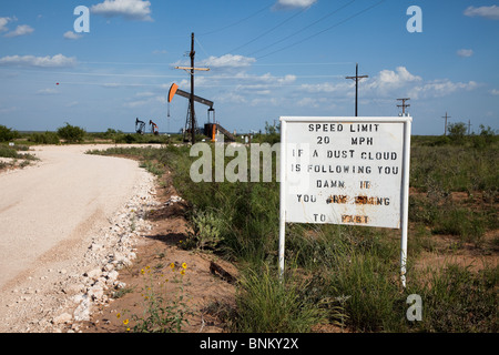 Speed limit sign on dirt road concening dust cloud in oil drilling area Eunice New Mexico USA Stock Photo