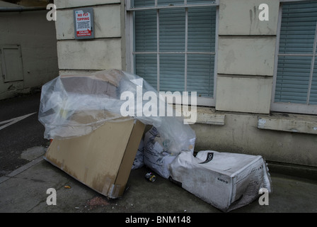 Fly tipping under a sign saying no fly tipping, on the London Road, Bath Somerset UK Stock Photo