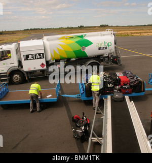 Aircraft fuel truck & baggage handler loading bags from a trolley onto an aircraft at Beziers International Airport S France Stock Photo
