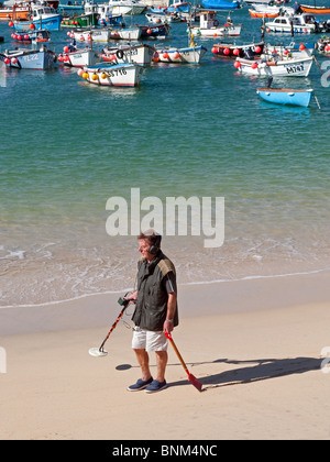 a man using a metal detector on the beach at st.ives in cornwall, uk Stock Photo