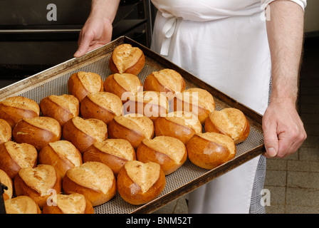 hands holding a tablet with baked bread rolls Stock Photo