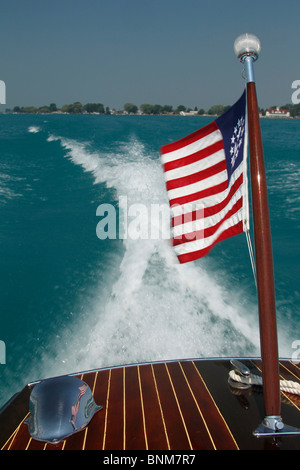 the mast and flag at the stern of a wooden boat cruising