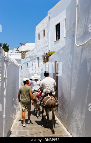 Tourists riding donkeys up to the Acropolis in the village of Lindos, Rhodes, Greece Stock Photo