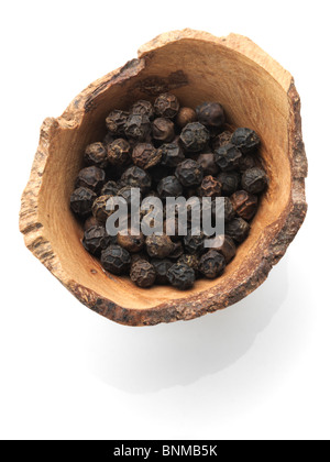 Black peppercorns in a wooden bowl on a white background Stock Photo