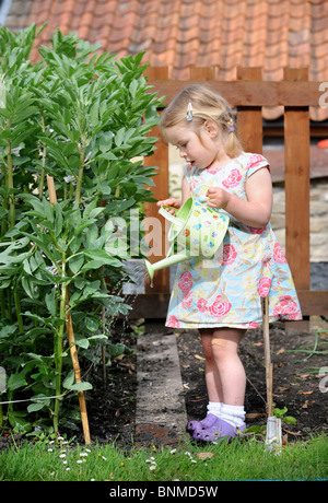 A young girl in a vegetable patch with a child's watering can UK Stock Photo