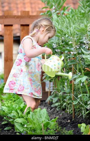 A young girl in a vegetable patch with a child's watering can UK Stock Photo