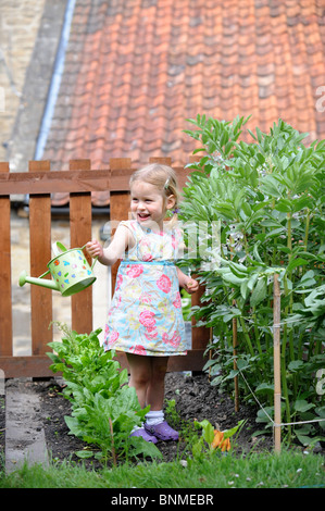 A young girl in a vegetable patch with a child's watering can UK Stock Photo