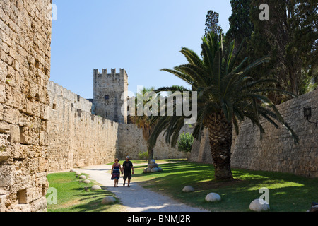 Couple walking along the path in the Medieval moat round the walls of the Old Town, Rhodes Town, Rhodes, Greece Stock Photo