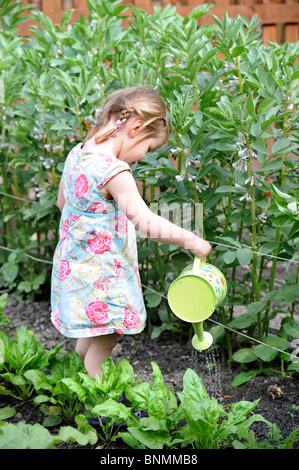 A young girl in a vegetable patch with a child's watering can UK Stock Photo