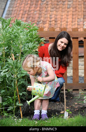 A young girl in a vegetable patch with a childs watering can UK Stock Photo