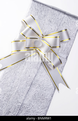 a pack wrapped in silver metallic paper, with a large bow tie, on white. Stock Photo