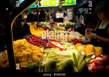 A stand selling a wide variety of fruit and berries displays its wares under bright lights in the night market in Taipei. Stock Photo