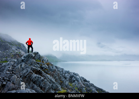 A lone hiker stands on a rocky outcropping overlooking Shoup Bay State Marine Park, Prince William Sound, Alaska Stock Photo