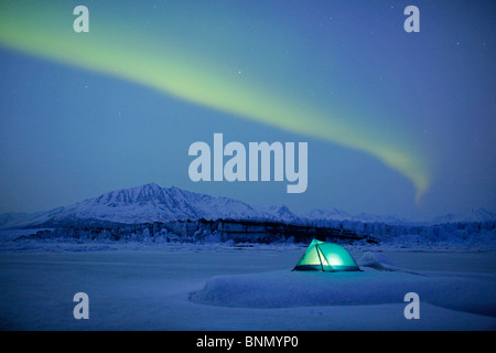 Northern Lights over lit tent on Knik Glacier, Alaska, Winter Stock Photo