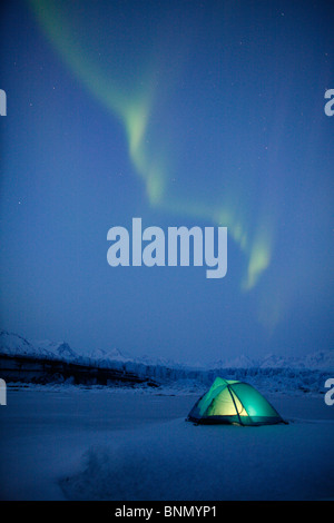 Northern Lights over lit tent on Knik Glacier, Alaska, Winter Stock Photo