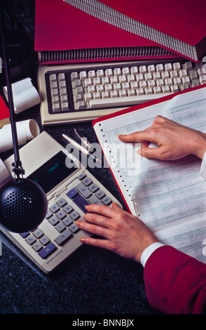 Office worker reviews statistics on computer print out forms. Stock Photo